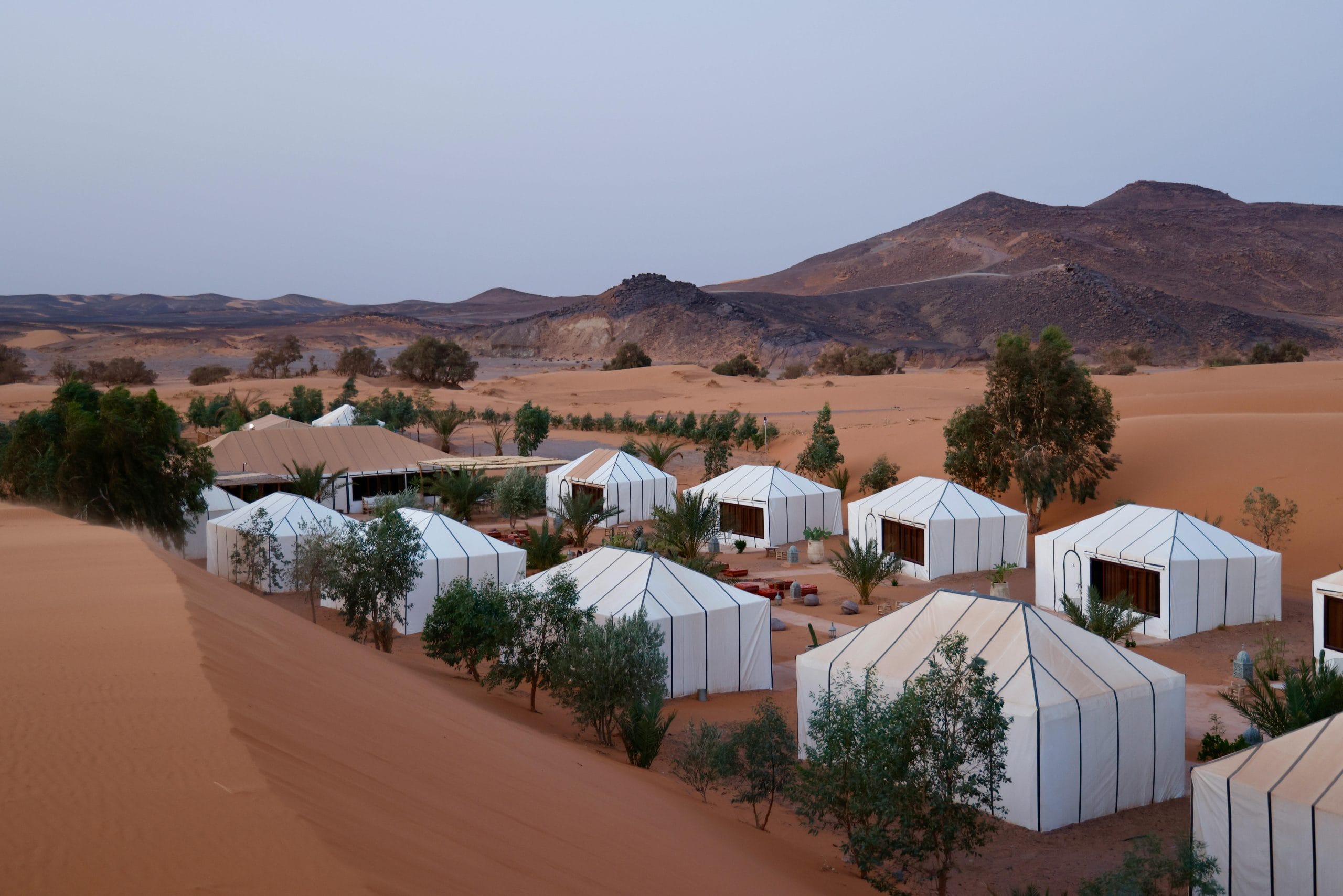A serene luxury desert glamping setup under a golden sunset