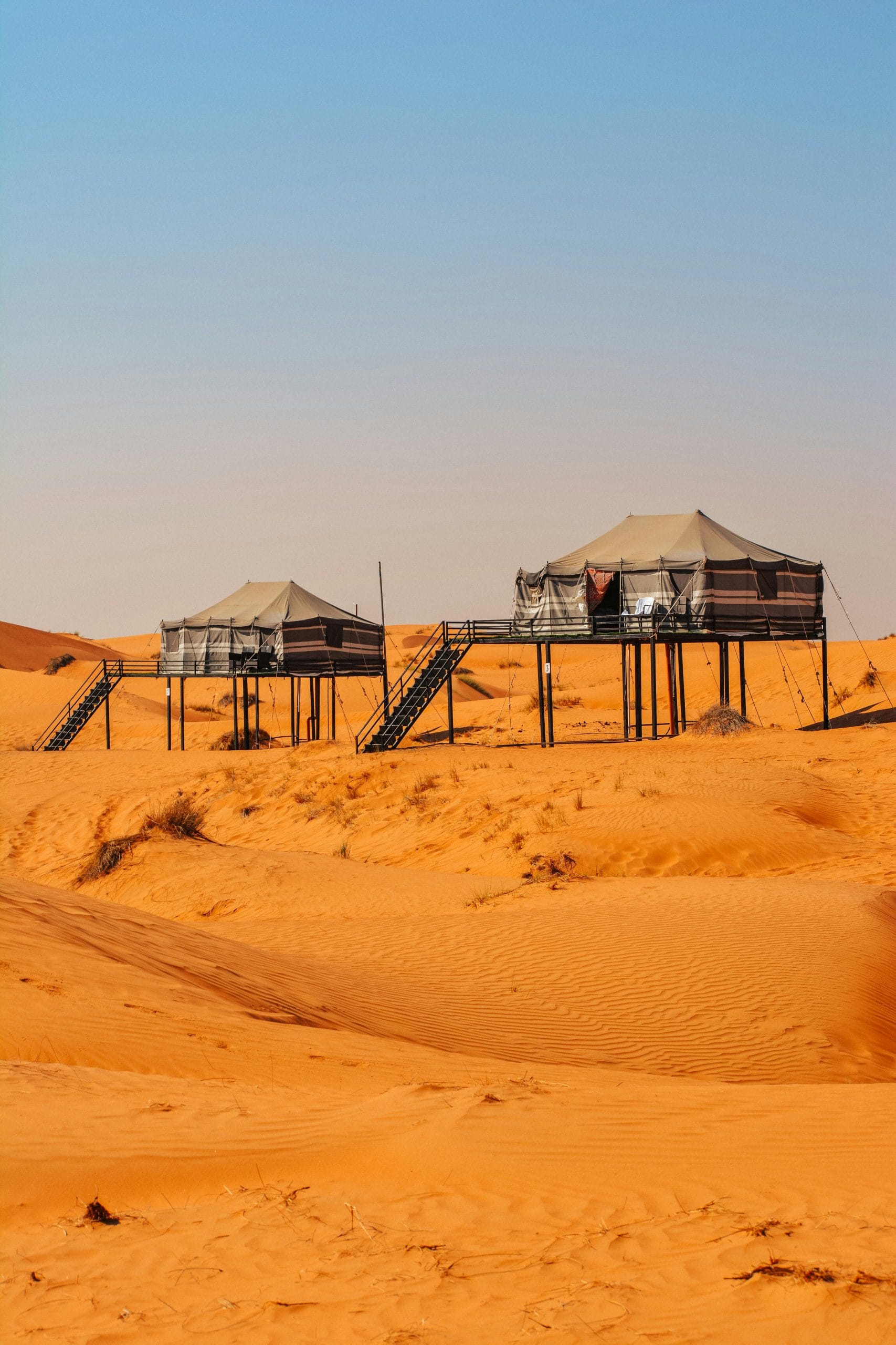 A serene luxury desert glamping setup under a golden sunset