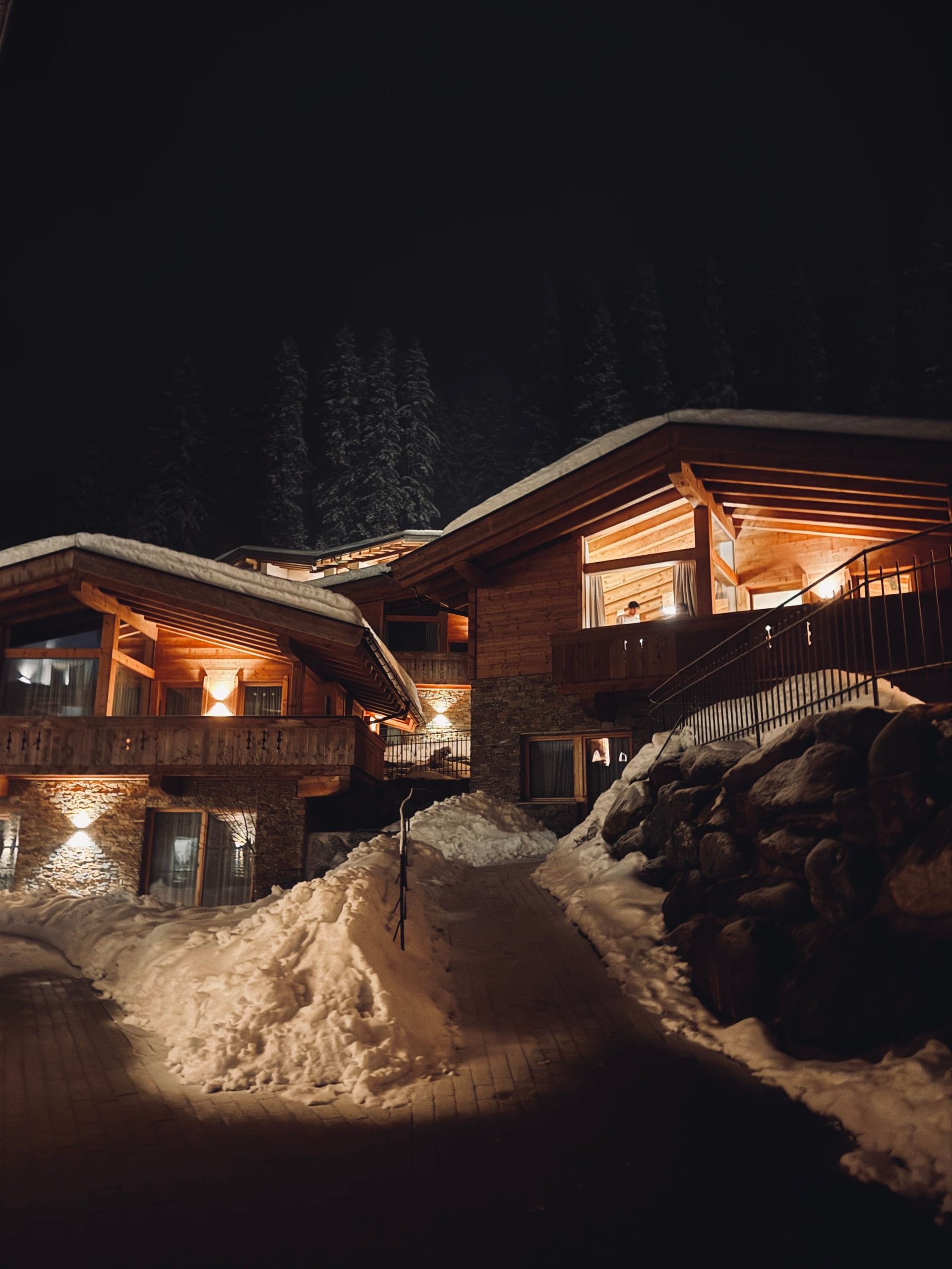 An elegant exterior of luxury mountain lodges overlooking a cinematic mountain range
